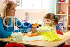 Teacher and little girl play with color paper