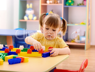 Little girl play with building bricks in preschool