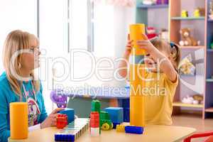 Teacher and preschooler play with building bricks