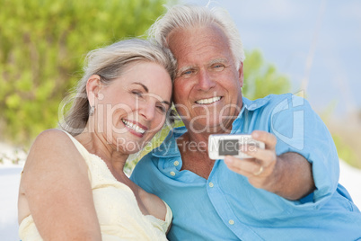 Happy Senior Couple Taking Photographs On Cell Phone At Beach