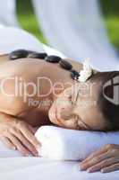 Woman Relaxing At Health Spa Having Hot Stone Treatment Massage