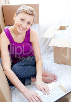 Smiling woman using a laptop in the living-room