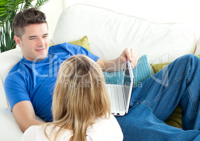 Young couple using a laptop together on a sofa