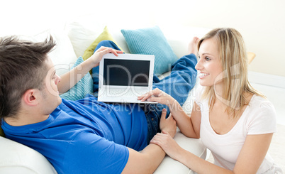 Charming couple using a laptop together on a sofa