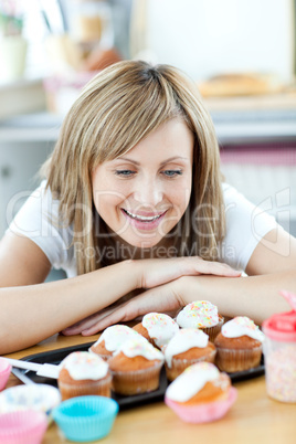 Cheerful woman looking at cakes in the kitchen