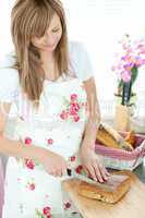 Cheerful woman cutting bread in the kitchen