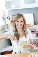 Portrait of a joyful woman preparing a cake in the kitchen