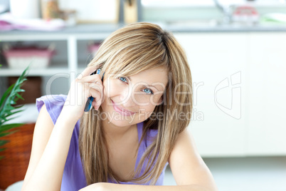 Portrait of a cheerful woman using a phone in the kitchen