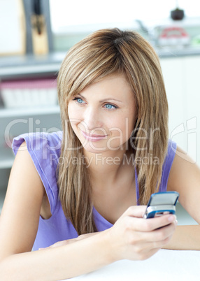 Delighted woman using a phone in the kitchen