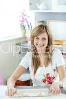 Portrait of a delighted woman preparing a cake  in the kitchen