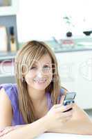 Teen woman sending a text in the kitchen