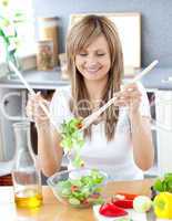 Smiling woman preparing a salad in the kitchen