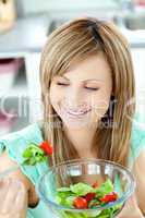 Young woman eating a salad in the kitchen