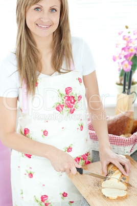 Delighted woman cutting bread in the kitchen