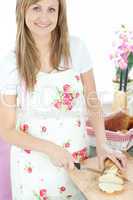 Delighted woman cutting bread in the kitchen