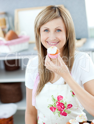 Delighted woman eating a little cake in the kitchen