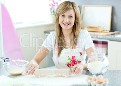 Delighted woman is preparing a cake in the kitchen