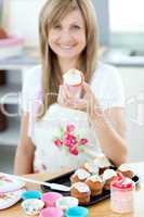 Young woman holding a cake in the kitchen