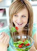 Cute woman eating a salad in the kitchen