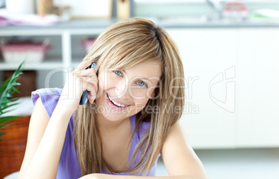 Smiling woman using a phone in the kitchen