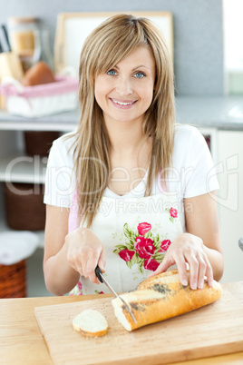 Smiling woman cuting bread in the kitchen