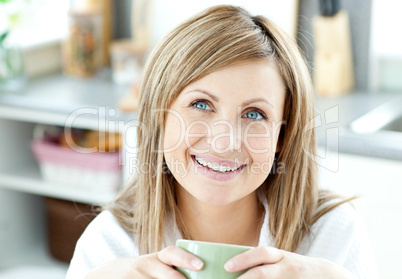 Happy woman holding a cup of coffee in the kitchen