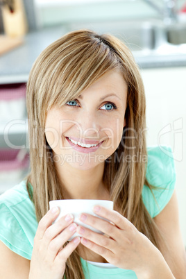 Self-assured woman holding a cup of coffee in the kitchen