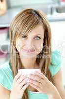 Confident woman holding a cup of coffee in the kitchen
