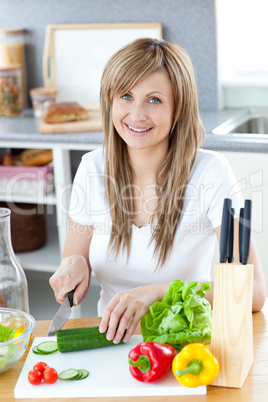 Delighted woman prapring a salad in the kitchen