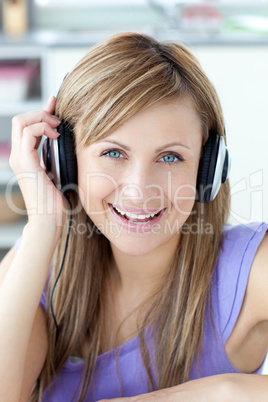 Delighted woman using headphone in the kitchen