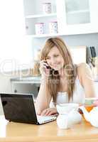 Delighted woman using a laptop in the kitchen
