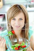 Radiant woman eating a salad in the kitchen