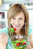 Delighted woman eating a salad in the kitchen