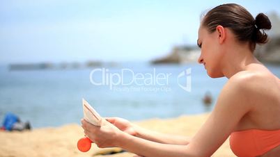 Woman on the beach applying lotion