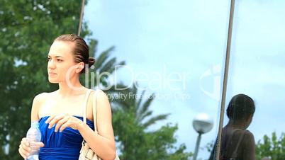 Woman drinking water against the background of office buildings