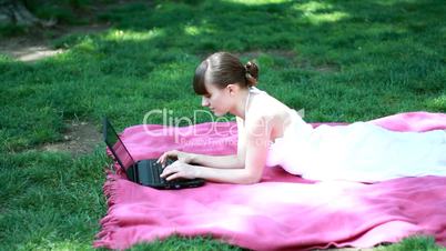 Woman with laptop lying in the park