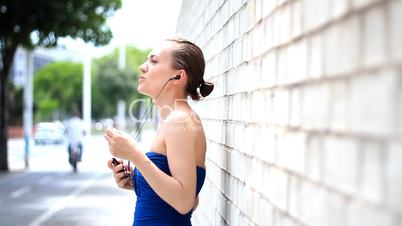 Woman with mp 3 player dancing against a wall