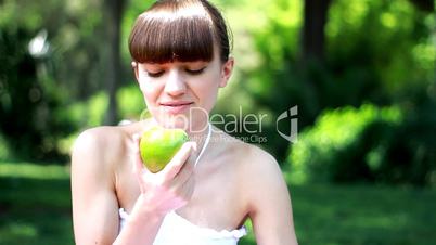 Young woman eats fresh apple outdoor