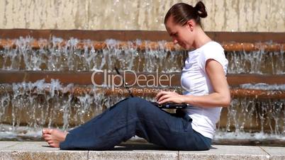 Woman with laptop sitting near the fountain