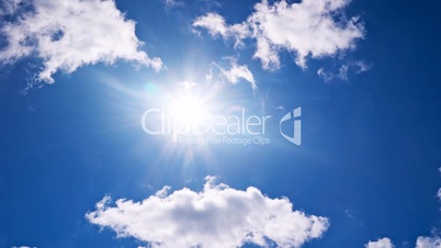 White clouds flying on blue sky with sun rays time-lapse