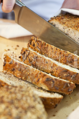 Close up of Slicing Rustic Wholemeal Seeded Loaf of Bread