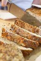 Close up of Slicing Rustic Wholemeal Seeded Loaf of Bread