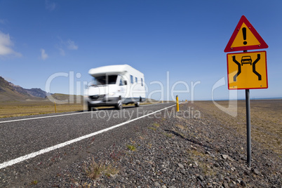 Motor Home Driving On An Open Road With Danger Sign