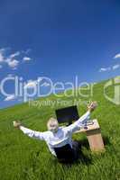 Businessman Celebrating Arms Raised At Desk In Green Field