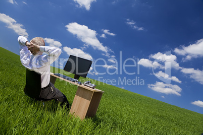 Man Relaxing At Office Desk In a Green Field