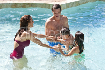 Happy Family With Two Children Playing In A Swimming Pool