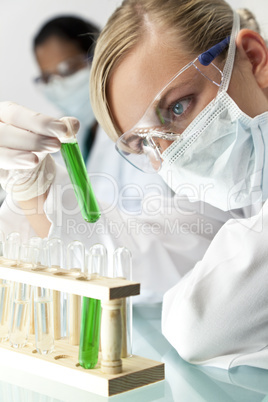 Female Scientist With Test Tube of Green Solution In Laboratory