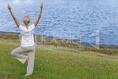 Beautiful Young Woman Practicing Yoga By A Tranquil Blue Lake