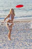 Beautiful Blond Woman In Bikini Playing Frisbee At The Beach