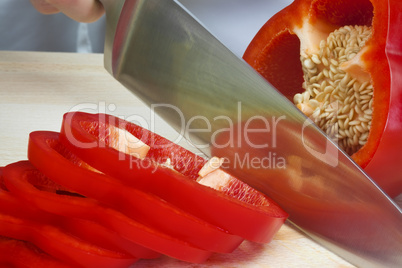 Chef In Kitchen Slicing A Red Pepper With Sharp Knife